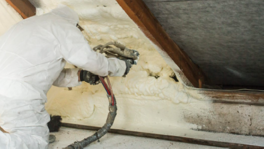 A person installs new insulation in their attic