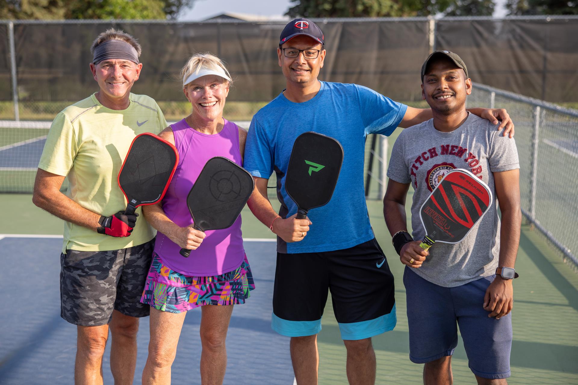 4 adult pickleball players posing for a photo together on the court