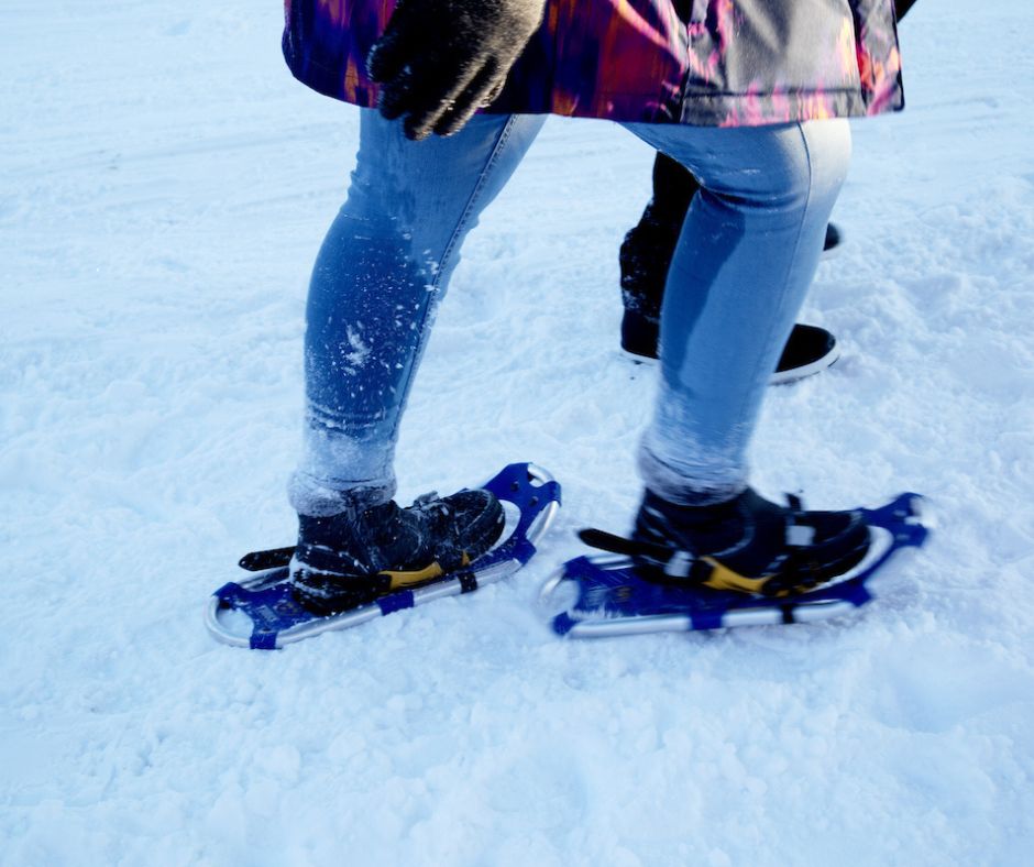 Close-up of a person walking through snow wearing snowshoes