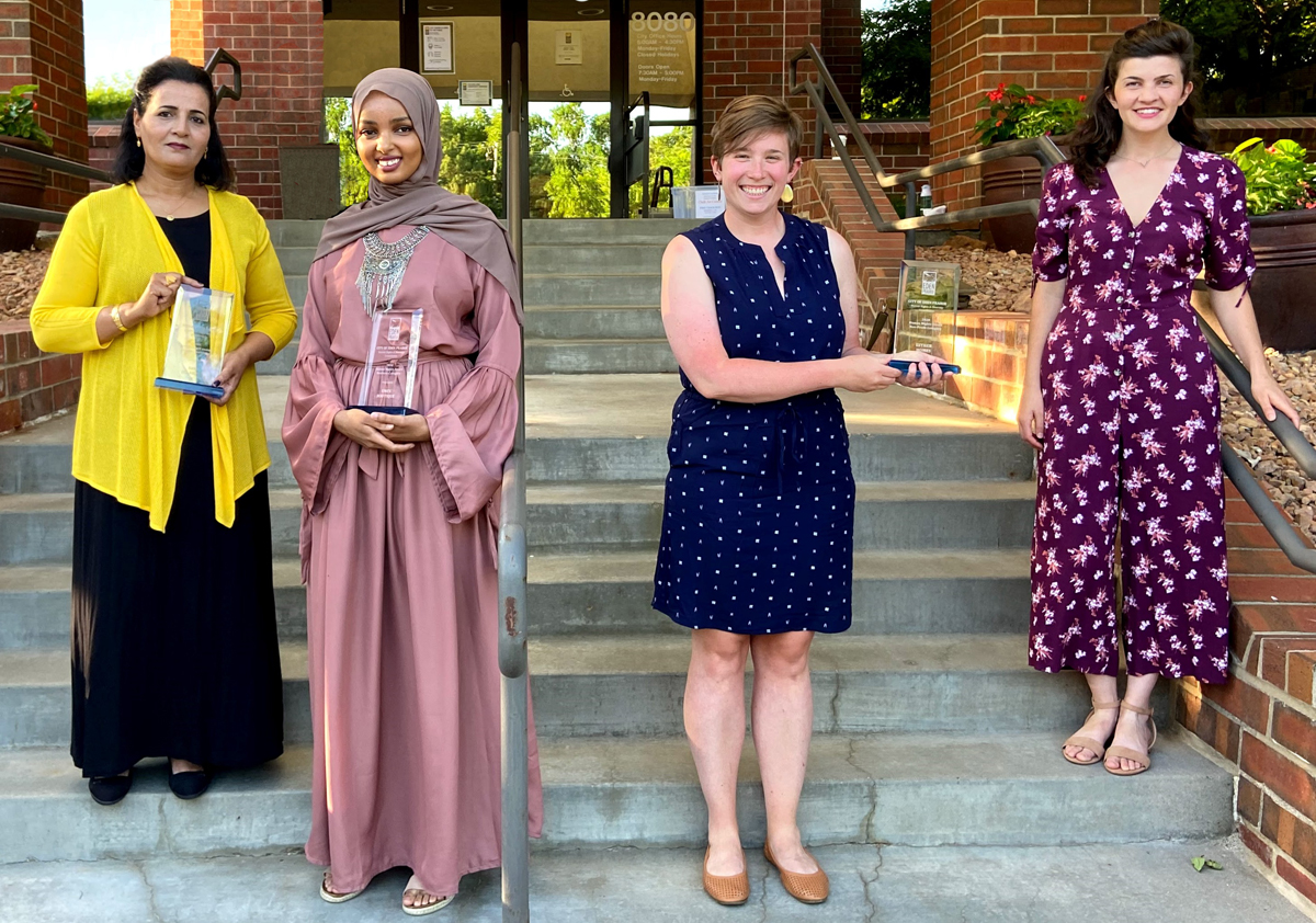 Four women holding plaques in front of City Hall