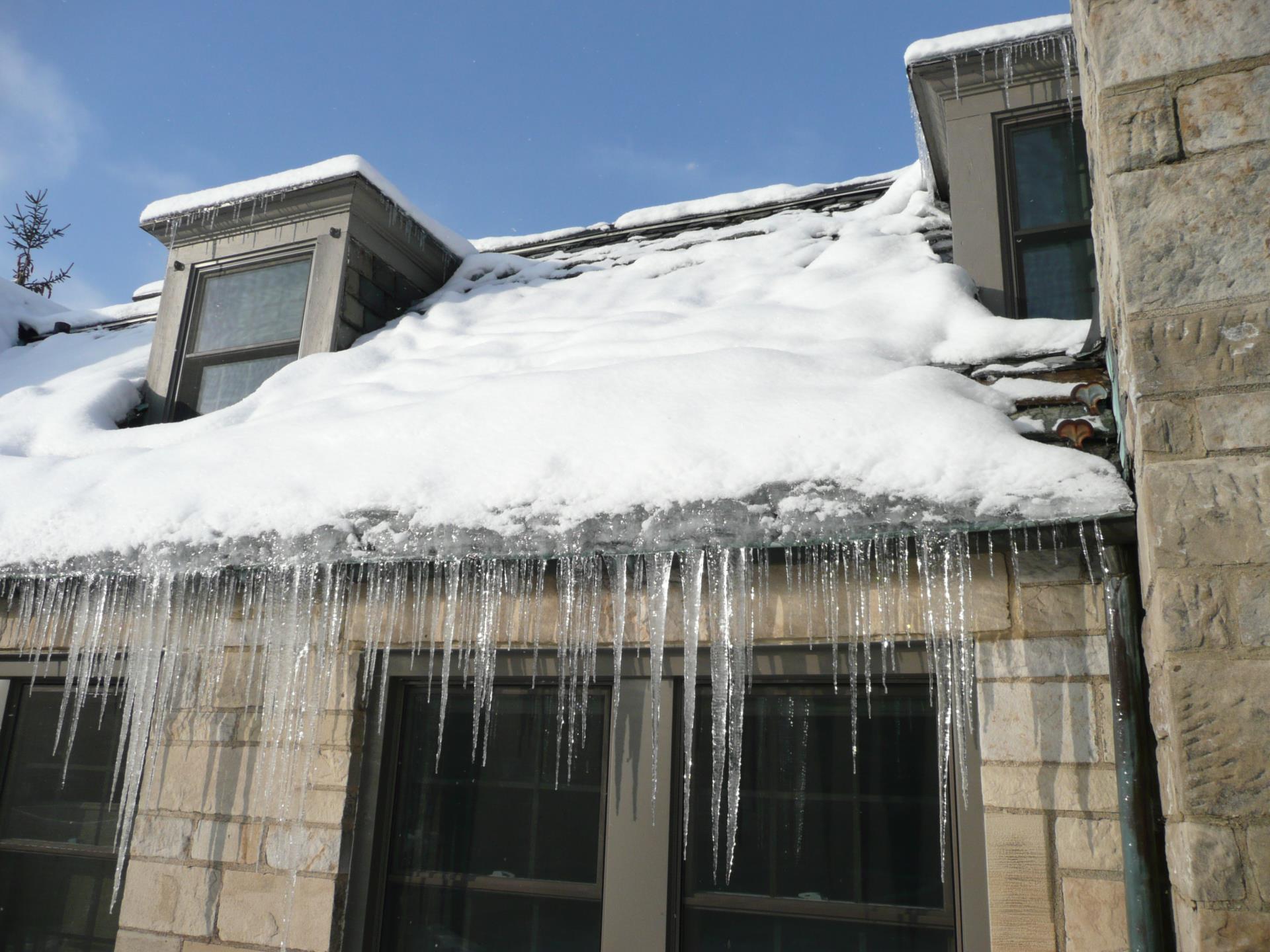 House with large icicles from snow-covered roof